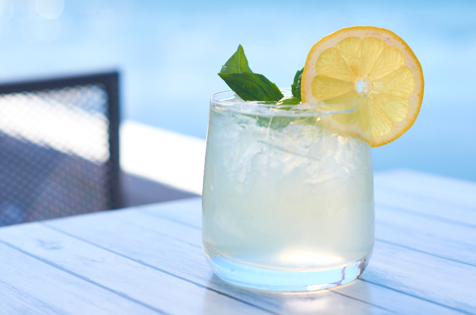 An iced lemon drink with mint on a poolside table