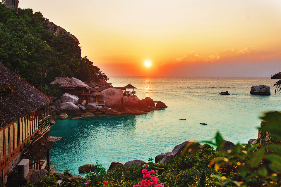 A small cove at sunset with boulders and seaside cottages