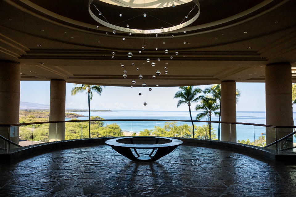 An open pavilion looking out to the sea and palms