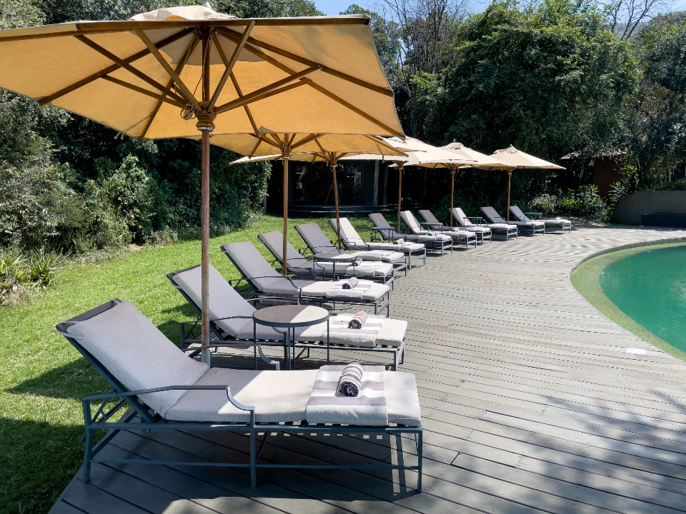 Sun loungers and umbrellas by a garden pool