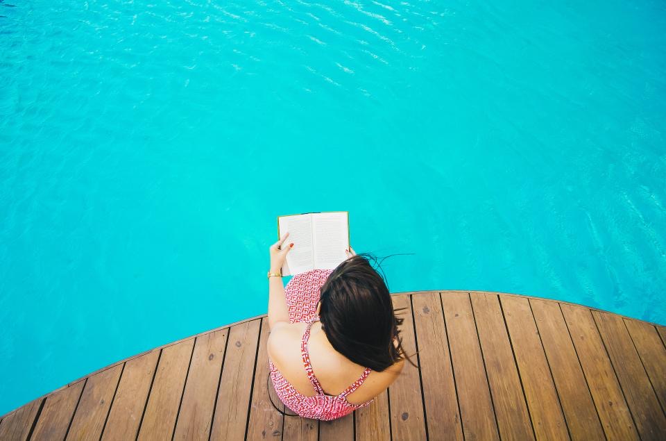 Someone reading at the edge of a turquoise pool