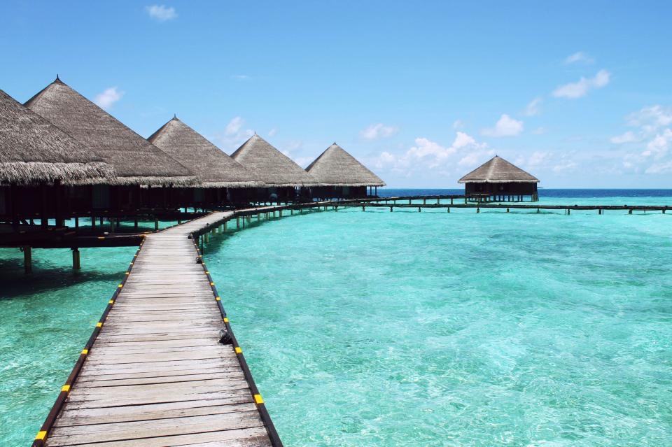 A timber walkway leading to villas over turquoise water